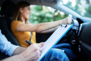 Free photo close up view of driving instructor holding checklist while in background female student steering and driving car