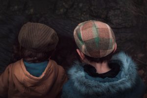 Photo closeup of two boys looking for something in the field in autumn back view