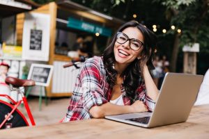 Free photo debonair white girl in casual shirt posing on street with computer. outdoor portrait of enthusiastic female student using laptop.