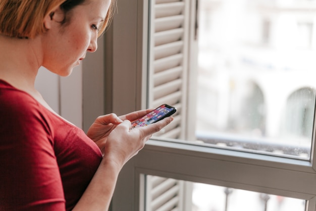 Free photo woman browsing smartphone near window