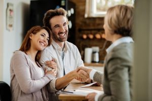 Free photo young happy couple came to an agreement with their insurance agent. focus is on man shaking hands with the agent.