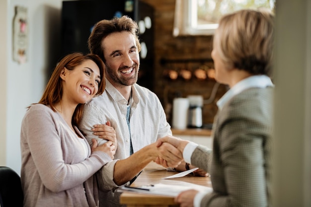 Free photo young happy couple came to an agreement with their insurance agent. focus is on man shaking hands with the agent.
