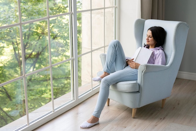 Free photo young woman holding her book while looking out the window
